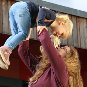 Frau in der Ausbildung zur Kinderpflegerin hält Kleinkind in die Höhe