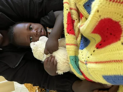 Patient mit Decke und Kuscheltier in Tansania